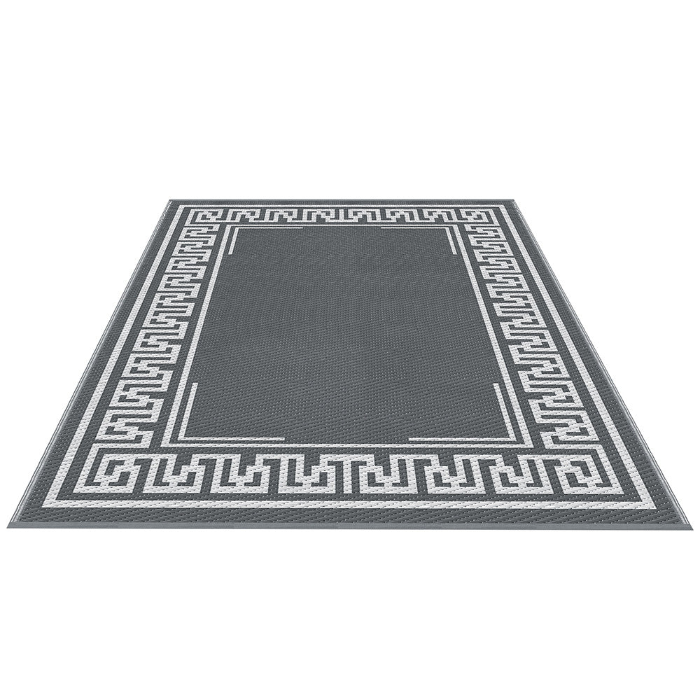 Angled view of the grey rectangular outdoor rug with a white Greek key border.