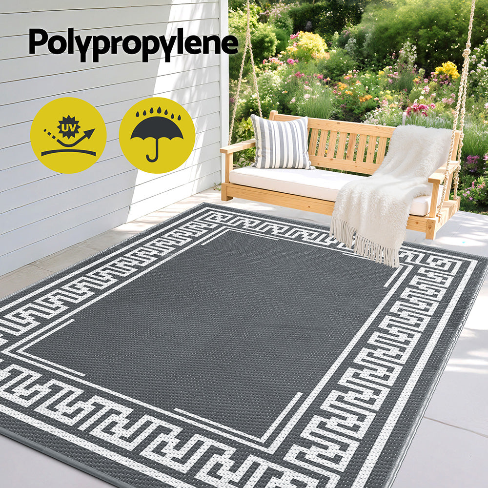 Grey Greek key outdoor rug beside a garden bench; bench and accessories not included.