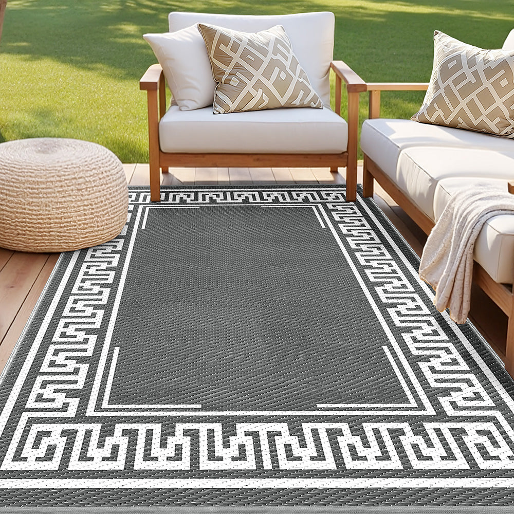 Grey outdoor rug with a white Greek key border beneath patio seating; furniture not included.